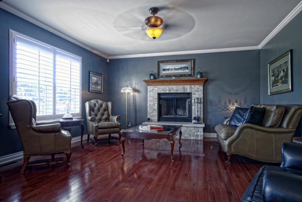 family room with hardwood flooring, blue walls, a stone fireplace and furniture